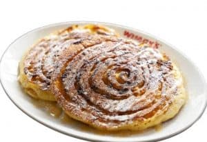 Delicious cinnamon swirl pancakes with powdered sugar on a white plate, served at a restaurant.