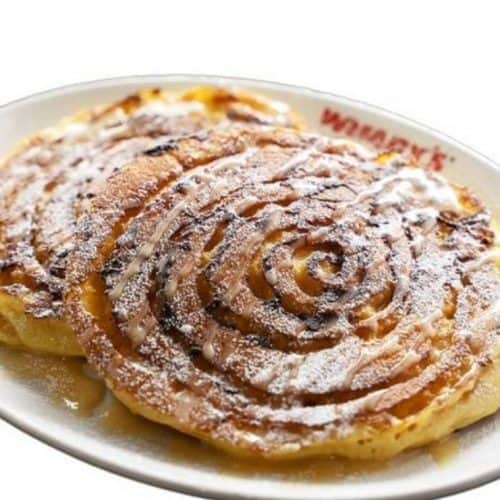 Delicious cinnamon swirl pancakes with powdered sugar on a white plate, served at a restaurant.
