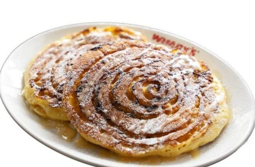 Delicious cinnamon swirl pancakes with powdered sugar on a white plate, served at a restaurant.