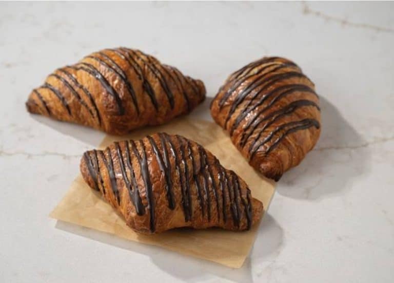 Buttery croissants drizzled with chocolate, fresh baked pastry, breakfast pastries, sweet croissants, homemade bakery treats.