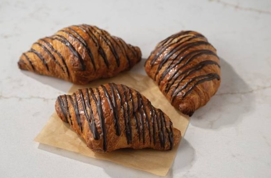 Buttery croissants drizzled with chocolate, fresh baked pastry, breakfast pastries, sweet croissants, homemade bakery treats.