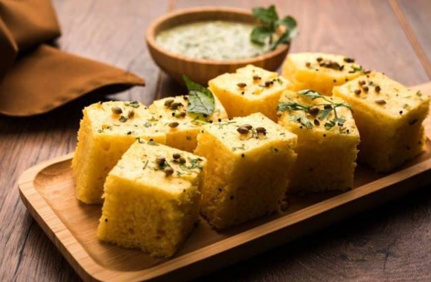 Fluffy Indian cornbread (Makai ka Saag) garnished with fresh herbs and black cumin seeds, served on a wooden platter with green chutney on the side, ideal for traditional Indian cuisine.