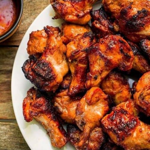 Succulent grilled chicken drumsticks with a flavorful roasted exterior, served on a white platter. Perfect for barbecues, gatherings, and flavorful dinner recipes.