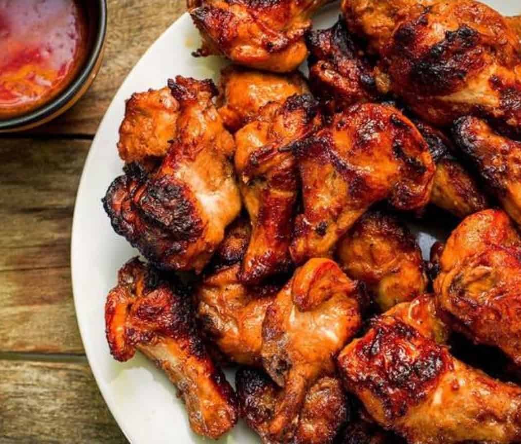 Succulent grilled chicken drumsticks with a flavorful roasted exterior, served on a white platter. Perfect for barbecues, gatherings, and flavorful dinner recipes.