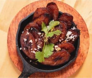 Crispy fried chicken wings garnished with cilantro and sprinkled with coarse salt served in a cast iron skillet on a wooden tray.