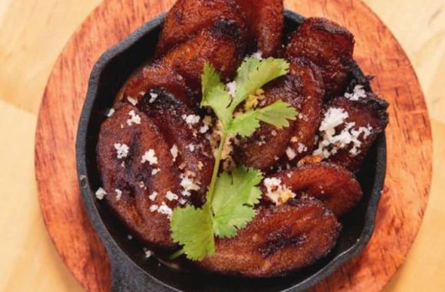 Crispy fried chicken wings garnished with cilantro and sprinkled with coarse salt served in a cast iron skillet on a wooden tray.